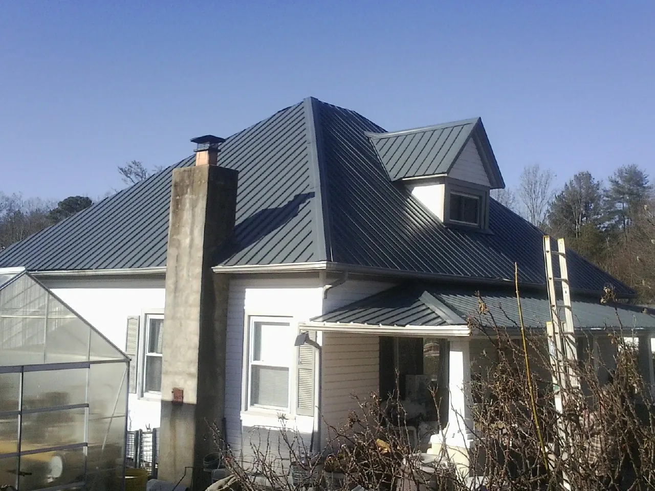 Dark blue standing seam metal roof on a white farmhouse with dormer — Slate & Tile Roof Repair by Roofing Brothers in Freehold