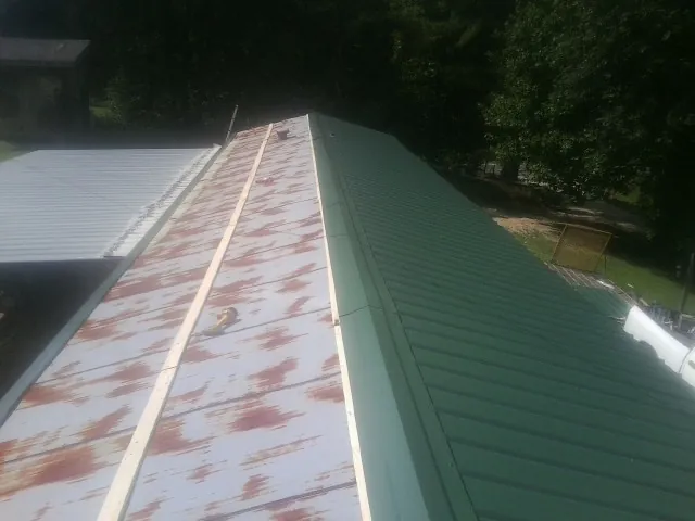 Old rusted panels beside newly installed green metal roofing — Wind Damage Roof Repair by Roofing Brothers in Freehold
