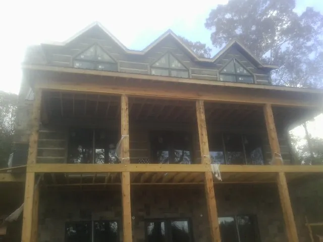 Dormers and porch framing on a large log home under construction — Roof Coating work by our crew in Freehold