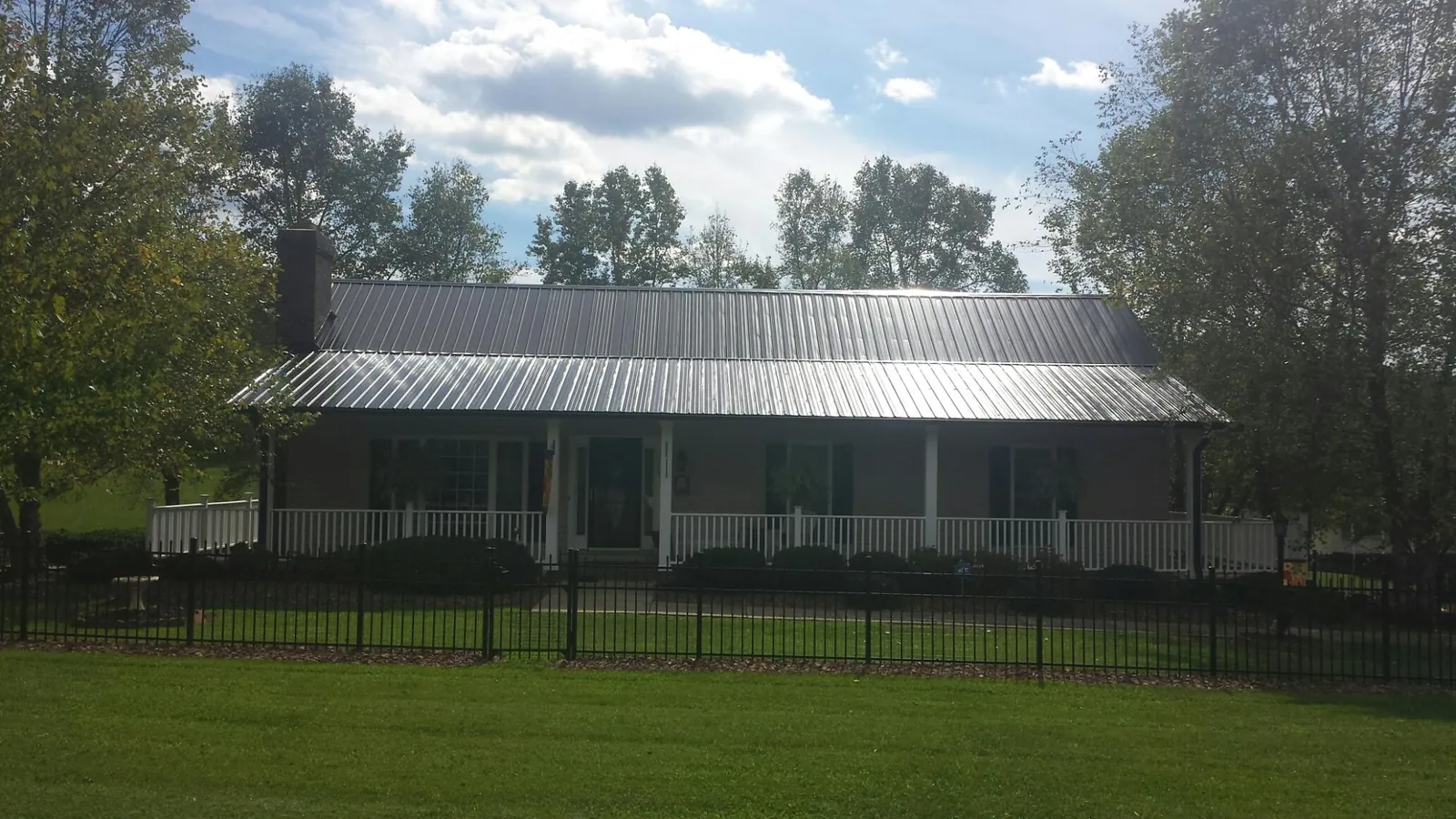Gray metal roof on a brick ranch with a full width front porch — Gutter Guard Installation work by our crew in Freehold