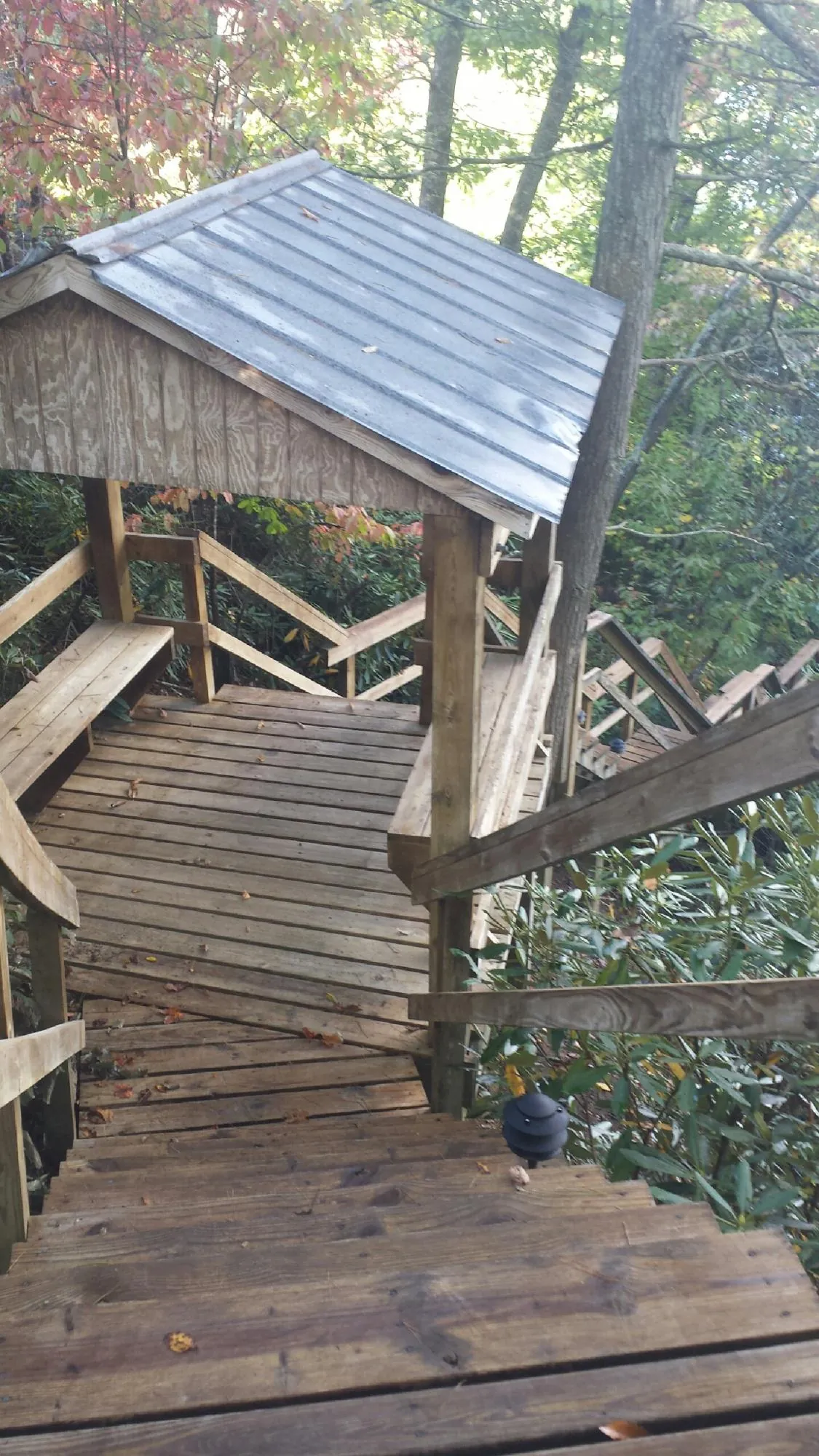 Metal roofed shelter over wooden steps on a wooded walkway — Skylight Repair & Installation work by our crew in Freehold