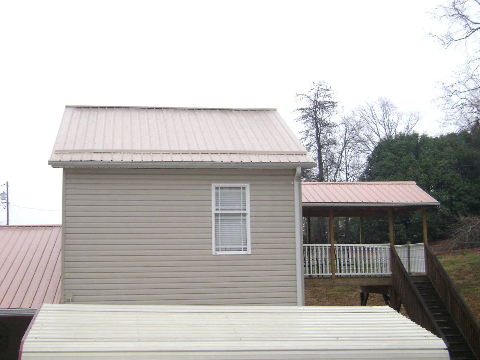 Tan metal roofs on a two story addition and attached porch, from a Roof Replacement job in Freehold