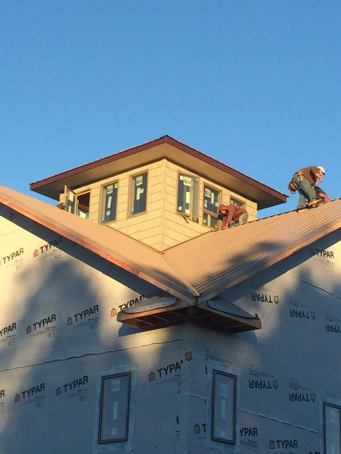 Roofers working around a rooftop cupola on a new metal roof at sunset — Roof Waterproofing in Freehold by Roofing Brothers